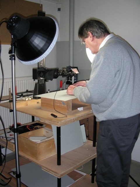 Herr Sauter an einer Werkbank, links daneben eine gro&szlig;e Scheinwerferlampe 