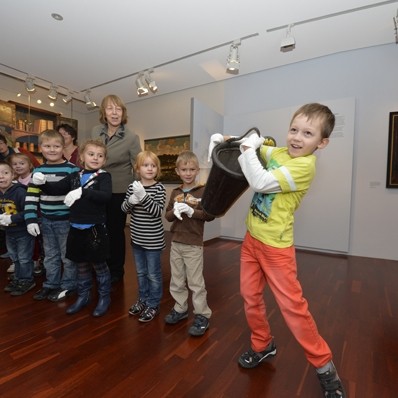 mehrere Kinder und eine Museumsp&auml;dagogin in der Abteilung Stadtgeschichte, ein Kind hat einen alten L&ouml;scheimer in den H&auml;nden, Link