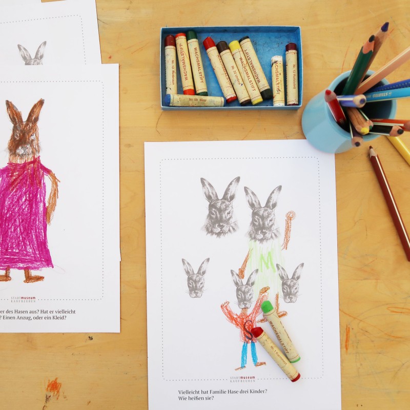 Schreibtisch mit Farbstiften und  zwei Bilder mit Osterhasen