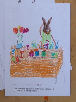 Kinderzeichnung eines Hasen vor einem Tisch mit Blumenvase und bunten Gl&auml;sern