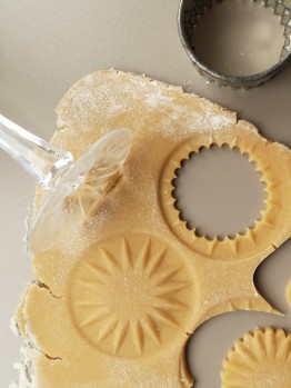 teilweise ausgestochener Keksteig mit Ausstechern und Glasfu&szlig;