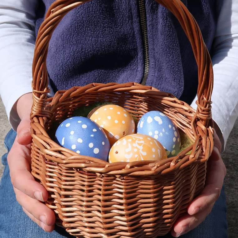 H&auml;nde halten einen Korb mit vier Ostereier darin