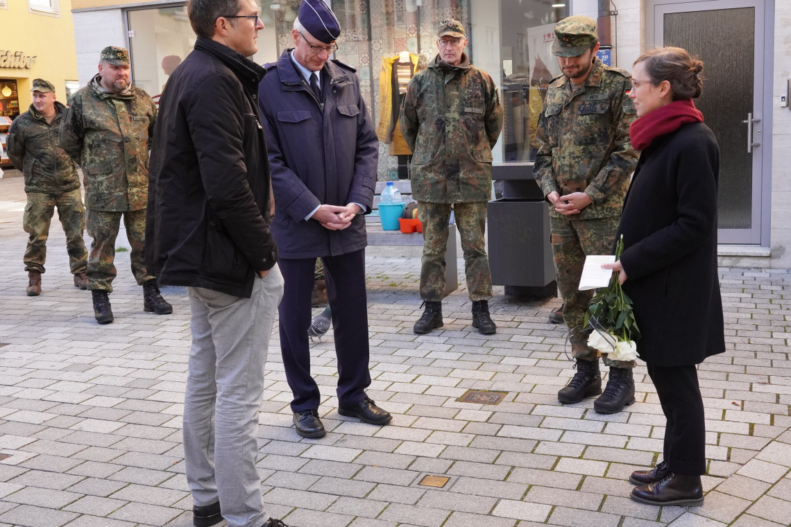 Oberst Martin Langer im Gespr&auml;ch mit Museumsleiterin Petra Weber und 2. B&uuml;rgermeister Oliver Schill, um einen Stolperstein stehend, dahinter vier Soldaten in Tarnanz&uuml;gen