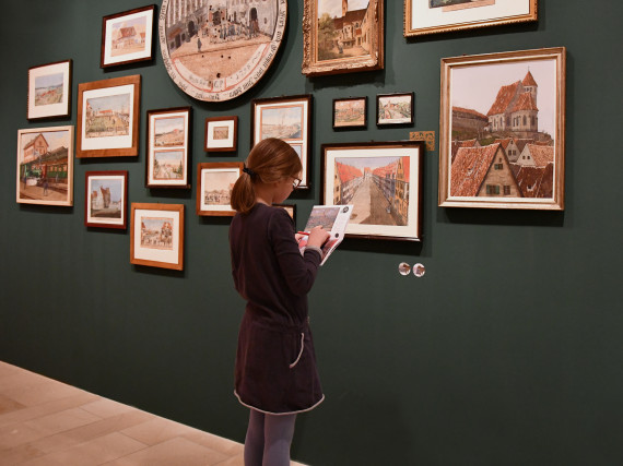 Ein M&auml;dchen in der Sonderausstellung "Wunschkonzert", welches Aufgaben im Mitmachheft l&ouml;st.          