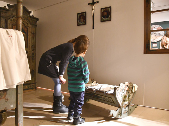 Ein M&auml;dchen und ein Bub sehen sich inder Sonderausstellung "Wunschkonzert" eine Wiege an