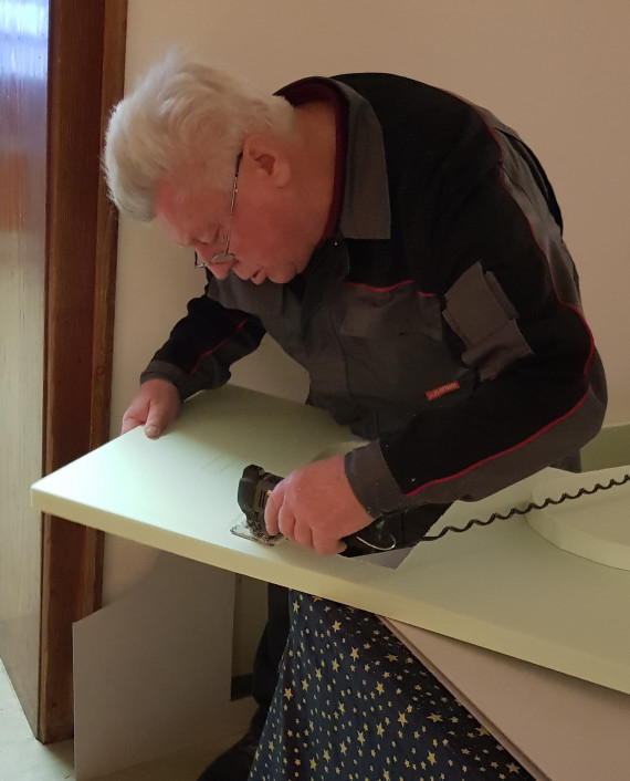 Ein Herr s&auml;gt mit einer kleinen elektrischen S&auml;ge etwas aus einem Brett