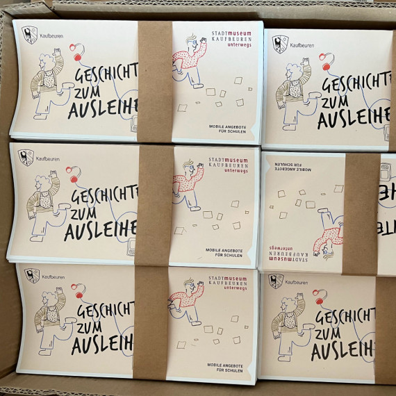 Foto eines Kartons mit geb&uuml;ndelten Faltbl&auml;ttern zu den unterwegs-Angeboten.